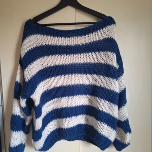 Randig stickad tröja från Design by Si - Säljer en mysig stickad tröja från Design by Si i blått och vitt. Tröjan har ett randigt mönster och är långärmad med en loose passform. 