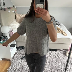 Grå stickad tröja från Stockholm - Säljer en mysig grå stickad tröja från Stockholm. Tröjan har korta ärmar och en ribbad struktur som ger en stilren look. Perfekt för kyligare dagar. 🩶