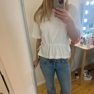 Vit hm T-shirt med knytning - Säljer en jättesnygg vit t-shirt med korta ärmar och knytband i midjan. Den är från hm och passar xs-s