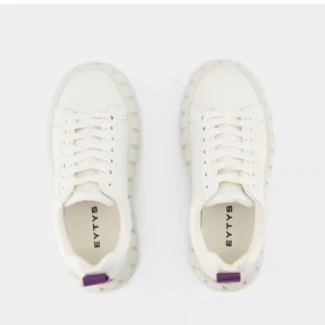 Vita sneakers från Eytys - Stilrena vita sneakers från Eytys med en chunky sula och klassisk snörning. Skorna har en unik design med lila detaljer på hälen som ger en modern touch. Rensar och säljer pga flytt. 