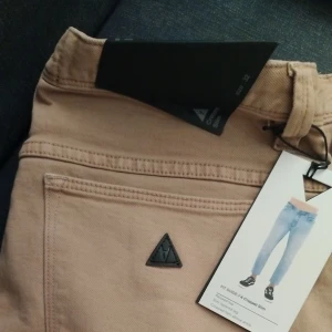 Beige chinos från Mac - Snygga beige chinos från Mac med en klassisk design. Byxorna har en normal passform och är perfekta för en stilren look. De har en diskret logga på bakfickan och bälteshällor i midjan.