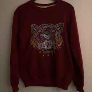 Vinröd sweatshirt från Kenzo - Säljer en vinröd sweatshirt från Kenzo med ett broderat tigerhuvud och texten 'Kenzo Paris' på framsidan. Skriv vid funderingar, kan gå ner i pris!