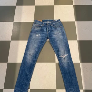 Dondup Jeans - Snygga blåa jeans från Dondup med en cool slitning på ena benet. Perfekta för en avslappnad stil med en touch av edge. Mycket eftertraktade och populära jeans! Mycket bra skick! Storlek 32! Hör av dig vid frågor och funderingar!!