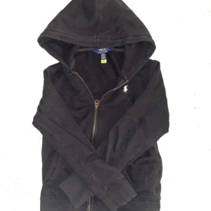 Svart huvtröja från Polo Ralph Lauren - Säljer en svart huvtröja från Polo Ralph Lauren med dragkedja och broderad logga på bröstet. Perfekt för en avslappnad stil. Passar på mig som är ca 148cm. Den har lite katt och hund hår på sig men den tvättas så klart innan den skickas💓