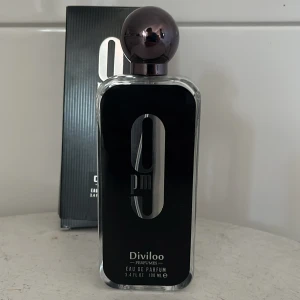 Byten? 9 PM Eau de Parfum från Diviloo - Säljer en elegant 9 PM Eau de Parfum från Diviloo. Flaskan är stilren med svart design och en rund, mörk kork. Innehåller 100 ml av en långvarig doft som passar perfekt för kvällsbruk. Förpackningen är svart med vit text.