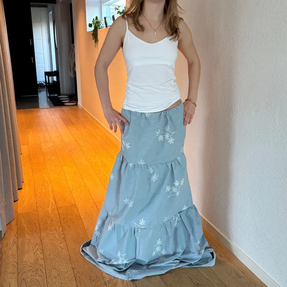 Säljer en ljusblå egensydd långkjol med ett vackert vitt blommönster.🩷💞Passar XS till M. Personen på bilden är 162 cm lång. Obs den är för lång på mig. Men den kan syns upp. Ställ gärna frågor och pris kan diskuteras.🫶🏼🫶🏼. Hameet.