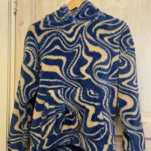 Blå och beige mönstrad hoodie från Lindex - Tröja från Lindex andvänd en gång, storlek 158-164.Perfekt för att hålla sig varm och stilren. Den har en mysig huva och långa ärmar.