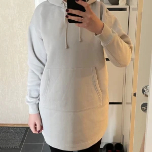 Grå ny hoodie från Peak Performance - Säljer en stilren beige hoodie från Peak Performance. Den har en känguruficka framtill och justerbar huva med dragsko. Perfekt för en avslappnad look. Passar bra till både jeans och leggings. 80 cm lång. Aldrig använd, endast tvättad. Kommer från djur&rökfritt hem. Mycket bra kvalité. Varm och härlig material. Storlek S.