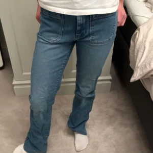 Blå jeans från Wrangler - MIDJEMÅTT: 35cm INNERBENSLÄNGD: 76 cmSnygga blå jeans från Wrangler med klassisk femficksdesign och broderad logga på bakfickan. De har en straight passform och är perfekta för en avslappnad stil. Jeansen har en hög midja och är tillverkade i slitstarkt denim.