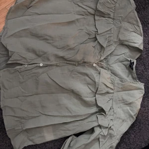 En grön blus med volanger - Säljer en grön blus från Lindex. Aldrig använd och är i nyskick. Den är lite skrynklig men jag kan stryka den innan den skickas. Pris kan diskuteras.💗