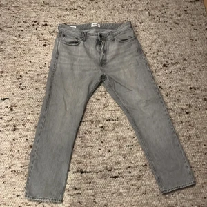 Grå jeans från Jack & Jones - Säljer ett par grå jeans från Jack & Jones i modellen Relaxed/Chris. De har en avslappnad passform och klassisk femficksdesign. Perfekta för en casual look.