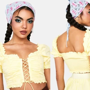 Gul topp från Dollskill - Butter Moving Too Fast Crop Blouse (märke: Mable), köpt på Dollskill för ca 654 kr och är slutsåld. Söt gul topp med spetsdetaljer och snörning framtill. Toppen är i en crop-modell och har puffärmar. Shirring i bak. Storlek S. Aldrig använd, endast testad men den kom utan tags.  Rökfritt hem men har katter.