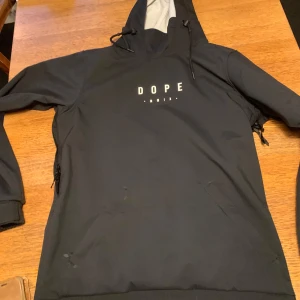Svart hoodie från Dope - Säljer en svart hoodie från Dope med tryck av ett berg och sol på ryggen. Har bara använts en gång.