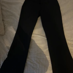 Svarta Lågmidjade kostymbyxor från Bik Bok - Snygga svarta Lågmidjade kostymbyxor  från Bik Bok med en klassisk design. Byxorna har en rak passform och är perfekta för en stilren look. De har hällor för bälte och en diskret dragkedja framtill. Passar M