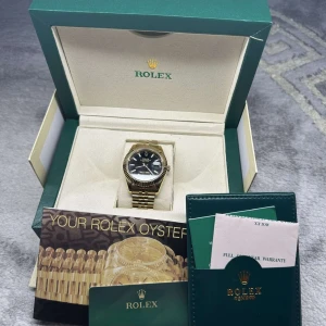 Klocka i guld färg - en automatisk klocka i rostfritt stål med en på 41mm. Låda Medkommer Den har safirglas och klarar upp till 100m djup i vatten.  För att hålla den igång behöver klockan dras upp var 48:e timme.  Snygg och i bra skick! För mer info kom pm 