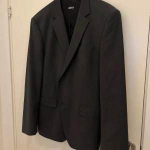 Grå kavaj från Hugo boss  - Säljer denna snygga kavaj från Hugo boss som endast är använd ett fåtal gånger. Modellen heter huge, dark grey. Nypris 3495, men säljer den för 1500kr