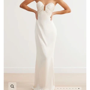 Balklänning satin, Krämvit axelbandslös - Elegant axelbandslös långklänning i krämvitt med draperad detalj vid bysten. Klänningen har en figurnära passform och är perfekt för ett baltillfälle. Använd en gång. Köpt för 2,828kr plus dyr frakt. 