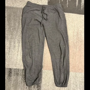 Grå mjukisbyxor med snörning - Säljer ett par bekväma grå mjukisbyxor med elastisk midja och snörning. Perfekta för en avslappnad dag hemma eller en snabb tur till affären. Byxorna har en loose passform och är gjorda i mjukt material.
