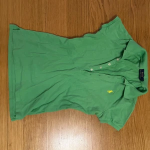 Grön polotopp från Ralph Lauren - Säljer en snygg grön polotopp från Ralph Lauren med krage och knappar framtill. Den har en liten gul logga broderad på bröstet. Snygg och sitter sååå fint på🙏🏻❤️💯