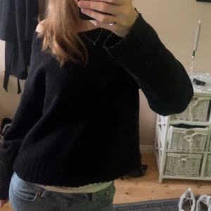 Svart stickad tröja - Säljer en stilren svart stickad tröja med långa ärmar och ribbade kanter. Perfekt för kyligare dagar och lätt att matcha med olika outfits. Passar både till jeans och kjol.