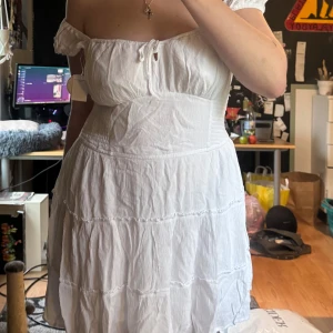 Vit axelbandslös klänning - Säljer min reserv student klänning. Oanvänd med lappar kvar. Shorts undertill och fickor på vardera sida. Är lite för stor storlek för mig. Om du vill ha fler bilder, mått eller frågor, hör av dig!