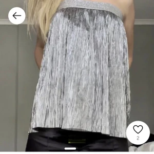 Glittrig axelbandslös topp - Snygg axelbandslös topp i silver med glittrig yta. Perfekt för festliga tillfällen. Den sitter uppe bra och är som ny! 