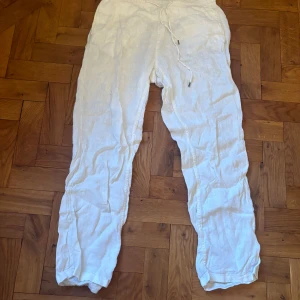 Vita linnebyxor från East West - Snygga vita linnebyxor från East West med avslappnad passform och snörning i midjan. Perfekta för varma dagar med sitt lätta och luftiga material. Byxorna har en enkel design med fickor på sidorna.