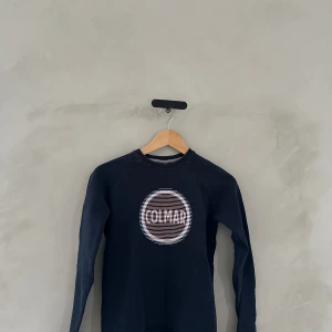 Mörkblå sweatshirt från Colmar - Säljer en snygg mörkblå sweatshirt från Colmar med deras ikoniska logga på bröstet. Tröjan har långa ärmar och en bekväm passform, perfekt för både vardag och chill. Passar bra till jeans eller joggers. Hör av dig vid intresse! 💙