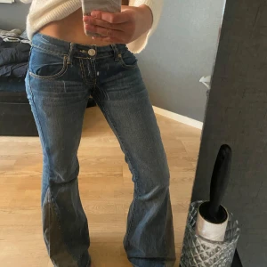 Väldigt lågmidjade mörkblå jeans  - Mörkblå med coola detaljer, har limmat fast diamanter på knappen hemma och sytt de så att det blev utsvängda själv med symaskin(kan skicka närbild privat). ( MIDJEMÅTT: 37-38cm) (INNERBENSLÄNGD:84 cm) Inte stretchigt material och långa på mig som är 168cm. Säljer pga rensar garderoben. Köpta här på Plick och står inte märke eller storlek men skulle säga XS . Lite slitet på lappen där bak men inget man tänker på, sen sytt själv där nere men annars bra skick.