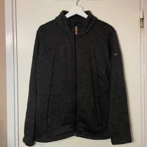 Fleecejacka från True North - Säljer en mörkgrå fleecejacka från True North i storlek L. Jackan har en dragkedja framtill och är långärmad, perfekt för kyliga höst- och vinterdagar. Den är i bra skick och supermjuk, idealisk för både vardag och utomhusaktiviteter.