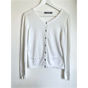 Vit finstickad kofta, M 38, bomull, klassisk, knappar, stilren, enkel, cardigan - Klassisk vit finstickad kofta, fuskfickor fram samt dekorativa knappar i ärmsluten. Finns en del ytslitage, svaga fläckar på överdelen fram samt fläck i nederkanten på insidan. Storlek: M, Bröstvidd: 44 cm,Axelbredd: 37 cm, Längd från axeln: 53,5 cm