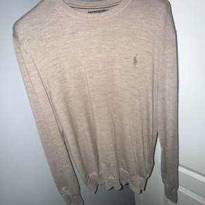 Beige tröja från Polo Ralph Lauren - Säljer en stilren beige tröja från Polo Ralph Lauren. Den är i slim fit och har långa ärmar. Perfekt för både vardag och lite finare tillfällen. Tröjan är i bra skick och har den klassiska loggan broderad på bröstet.