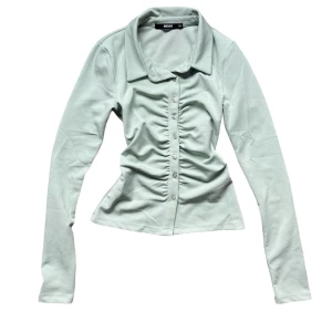 Ljusgrön långärmad topp från Bik Bok - Säljer en superfin ljusgrön långärmad topp från Bik Bok. Den har en snygg krage och knappar hela vägen ner. Använd fåtal gånger och i fint skick, har 2 defekter som visas på de 2 sista bilderna. Storlek: XS