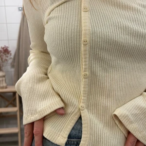 Asymetrisk topp med knäppning - Havrefärgad topp med lite vida armar.  Toppen är aldrig använd med prislapp kvar.   Den är gjord utav polyester,bomull och elastan 