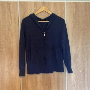 Kashmir zip hoodie - Säljer en snygg och bekväm mörkblå 100% kashmir zip hoodie från Lawrence grey. Den har en dragkedja framtill och är perfekt för både höst och vår. Tröjan är långärmad och gjord i kashmir som håller dig varm. Perfekt för en avslappnad stil!