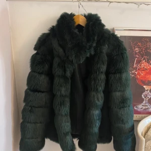 Grön pälsjacka  - Jätte fin och mysig mörkgrön pälsjacka (inte riktig päls!) i mycket fint skick!💕 Storlek 38  Skriv gärna om ni undrar något eller vill ha fler bilder💕 100% akryl (inte riktig päls) Endast använd några gånger 
