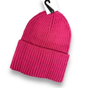 Rosa stickad mössa - Säljer en superfin rosa stickad mössa som är perfekt för att hålla värmen under kalla dagar. Den har en ribbad design som ger en snygg och stilren look. Passar perfekt till både höst och vinteroutfits!