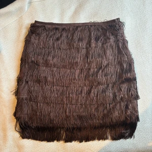 Brun kjol med fransar - Skitsnygg kjol från NA-KD som endast är använd få gånger. Storlek 38, köparen står för frakten 🤎