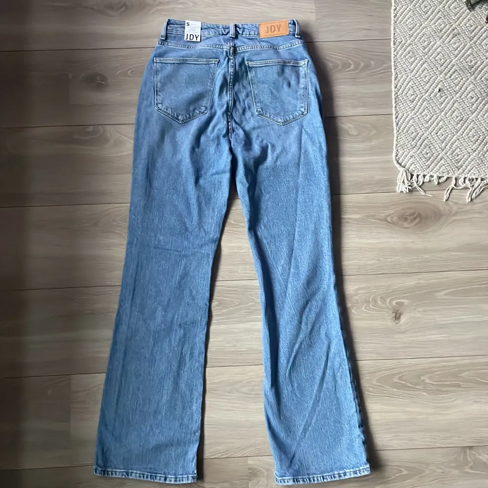 Säljer ett par snygga blå jeans från JDY i storlek S. De är högmidjade och har en flared stil som ger en cool retrovibe. Perfekta för både vardag och fest! 🦋. Jeans & Byxor.