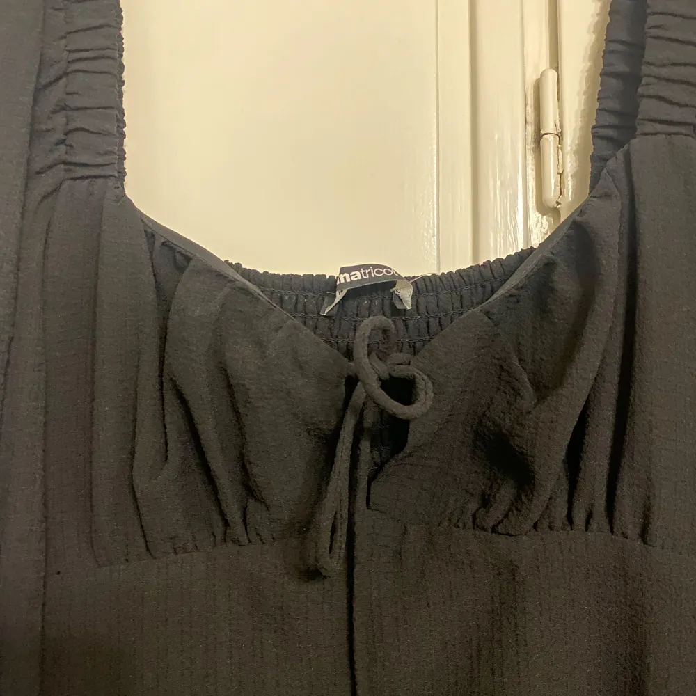 Snygg svart långklänning från Gina Tricot i nytt skick. Klänningen har långa ärmar och en smockad detalj vid bysten som ger en fin passform. Perfekt för höst och vinter, och kan stylas både upp och ner beroende på tillfälle. Ett måste i garderoben för den som älskar stilrena plagg!. Mekot.