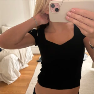 Svart croppad topp - Säljer en snygg svart croppad topp med korta ärmar och en stilren design.😊😊😊💓🥰💓🥰🥰