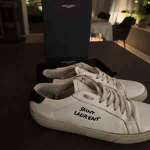 Saint Laurent sneakers  - Säljer ett par vita sneakers från Saint Laurent i mycket bra skick. Skorna har en stilren design med svart detalj vid hälen och Saint Laurent-logga på sidan. Perfekta för både vardag och fest! Har tyvärr inget kvitto därav priset. Skriv gärna vid minsta fundering. mvh/casper