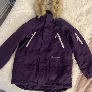 Lila vinterjacka med pälsdetaljer - Säljer en snygg lila vinterjacka från Didriksons. Den har en mysig pälsdetalj på huvan och flera praktiska fickor med dragkedja. Perfekt för kalla vinterdagar! Jackan är i mycket bra skick och redo för nya äventyr. Passar perfekt för vinterns alla aktiviteter ❄️