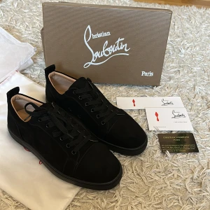 Christian Louboutins- Dior - Säljer ett par helt nya, exklusiva Christian Louboutin sneakers i storlek 43. Skorna är i svart mocka med den ikoniska röda sulan och klassisk snörning, perfekt för både vardag och fest. De kommer med originalförpackning, dustbags och alla intakta originalkort, vilket gör detta till ett oslagbart erbjudande för den som söker kvalitet och stil. Ett unikt tillfälle att äga ett par lyxiga och aldrig använda Louboutin-skor i nyskick, som garanterat kommer att höja din garderob.