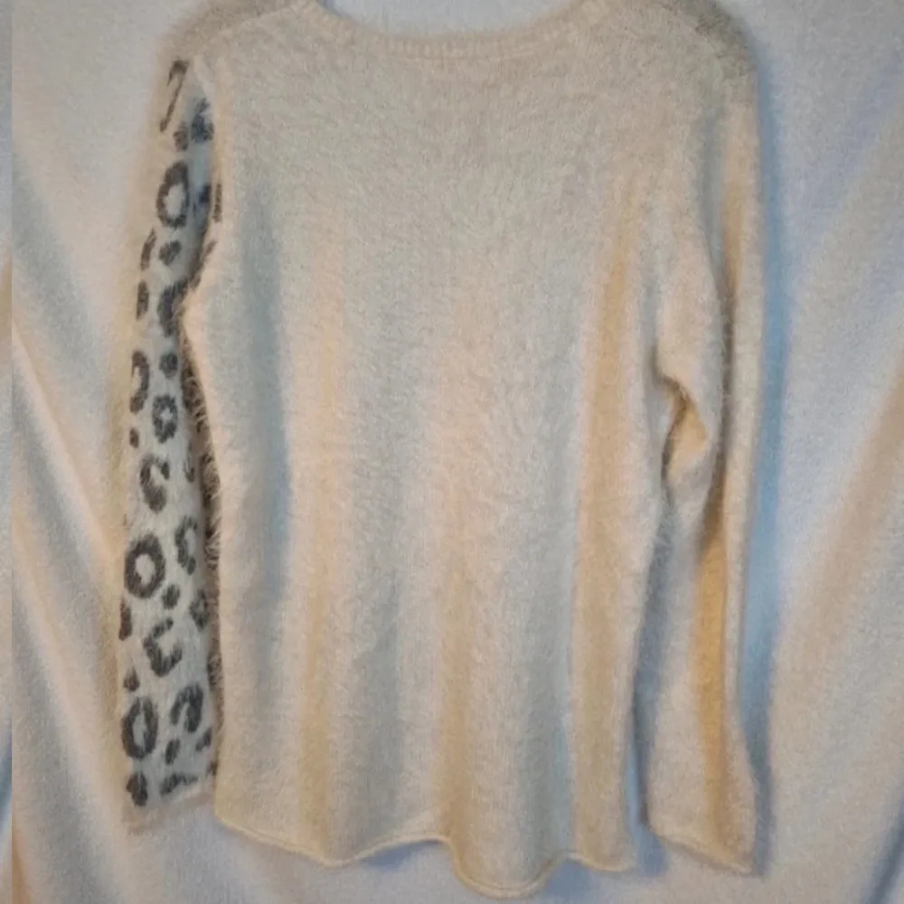Vit stickad tröja med leopardmotiv som är lite lurvig. Storlek 158/164 från HM. Mycket fint skick.. Neuleet.