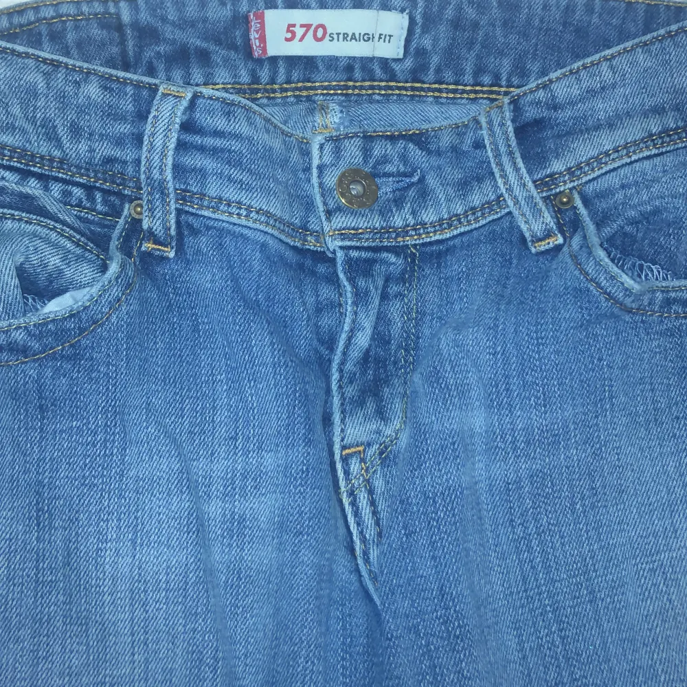 Säljer ett par klassiska Levis 570 jeans i straight fit. De är blå och har en snygg, avslappnad stil. Perfekta för vardagsbruk och passar till det mesta. Jeansen har en knappgylf och fem fickor.Jeansen har bara en eyeliner fläck innuti men syns ej när man har de på sig!Säljer de eftersom jag ej använder de❤️💕kontakta om du har frågor!. Jeans & Byxor.