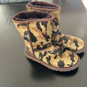Camouflage boots från UGG - Säljer ett par supercoola UGG boots i camouflage-mönster. De är fodrade med mjuk päls och har snygga nitar på baksidan. Perfekta för att hålla fötterna varma och stiliga under hösten och vintern. Använda men i bra skick!