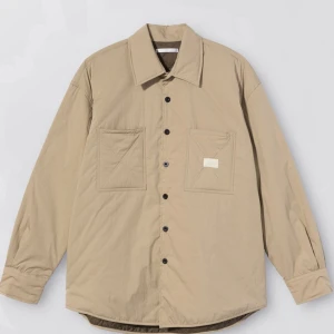 Our legacy x stussy fatigue shirt  - Säljer en snygg beige overshirt med knappar och två stora fickor fram. Perfekt för lager-på-lager under hösten eller våren. Den har en avslappnad passform och är långärmad. Materialet känns slitstarkt och bekvämt. Passar både till vardags och lite mer uppklädda tillfällen.