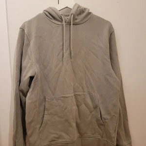 Ljusgrön hoodie från Dressmann - Säljer en stilren ljusgrön hoodie från Dressmann i storlek M. Den är i bra skick och perfekt för både höst och vår. Hoodien har en klassisk design med en ficka på magen och justerbar huva med snören. Perfekt för en avslappnad look!