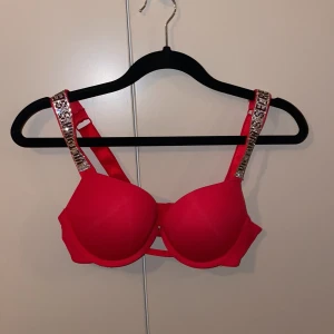 Röd bh från Victoria's Secret - Säljer en snygg röd bh från Victoria's Secret med glittriga axelband. ALDRIG använd då jag råkade beställa fel strlk, strlk 75b! Har även i svart blå och rosa